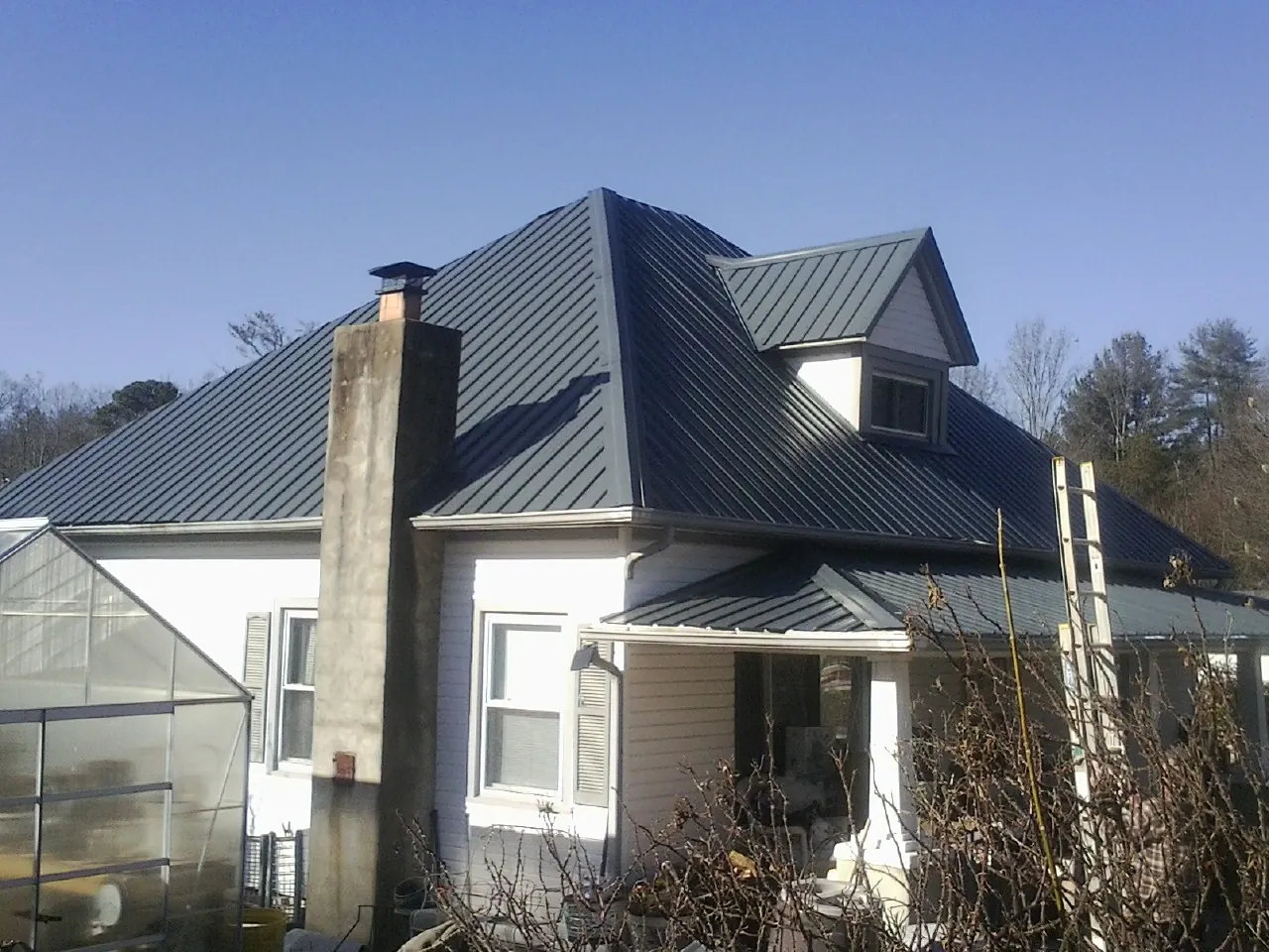Dark blue standing seam metal roof on a white farmhouse with dormer — Slate & Tile Roof Repair by Roofing Brothers in Hanahan
