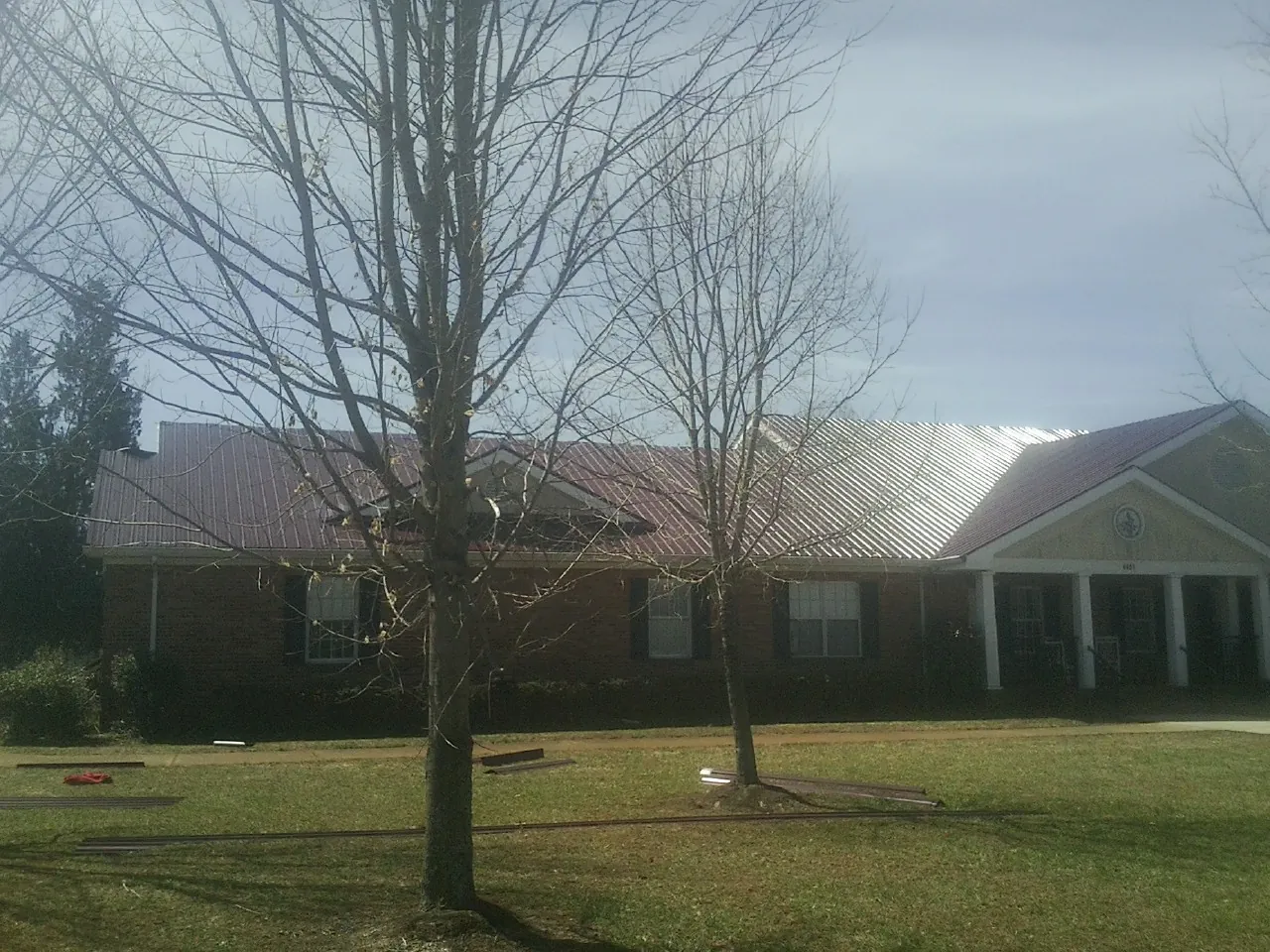 Red metal roof on a brick building seen from the front lawn in Hanahan