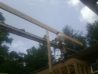 Carpenter setting a ridge beam over a new addition frame — Ice Dam Removal by Roofing Brothers in Hanahan