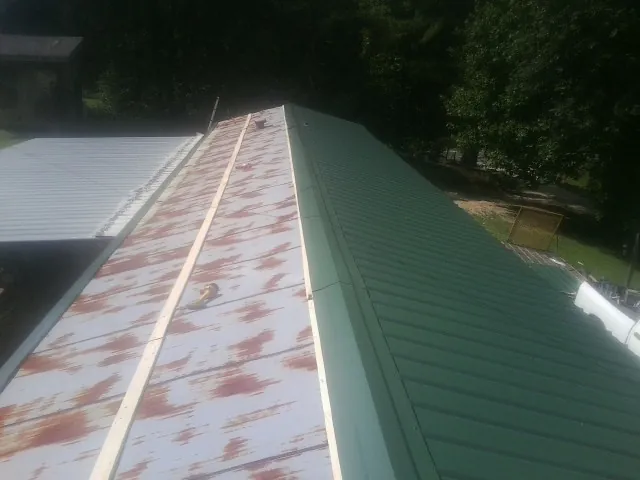 Old rusted panels beside newly installed green metal roofing — Wind Damage Roof Repair by Roofing Brothers in Hanahan