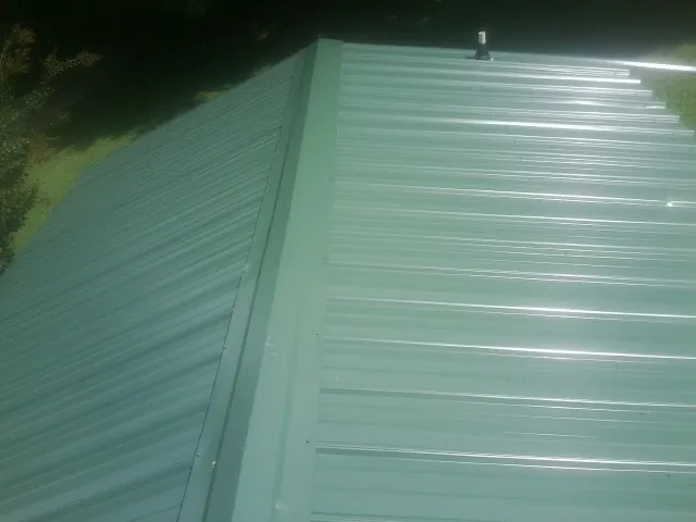 New green metal panels meeting at the ridge of a roof — Flat Roof Repair work by our crew in Hanahan