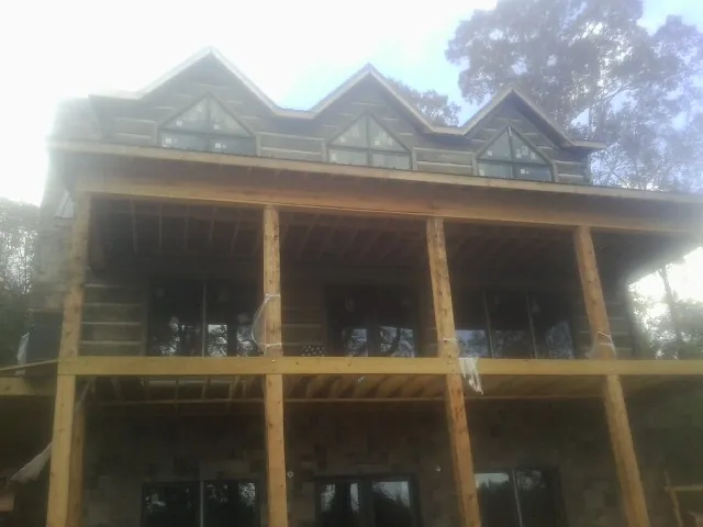 Dormers and porch framing on a large log home under construction — Roof Coating work by our crew in Hanahan