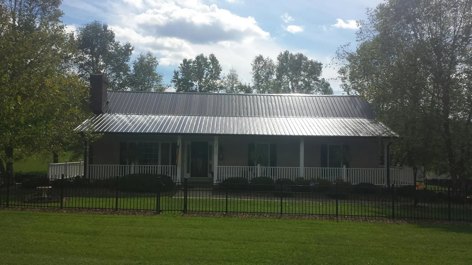 Gray metal roof on a brick ranch with a full width front porch — Gutter Guard Installation work by our crew in Hanahan