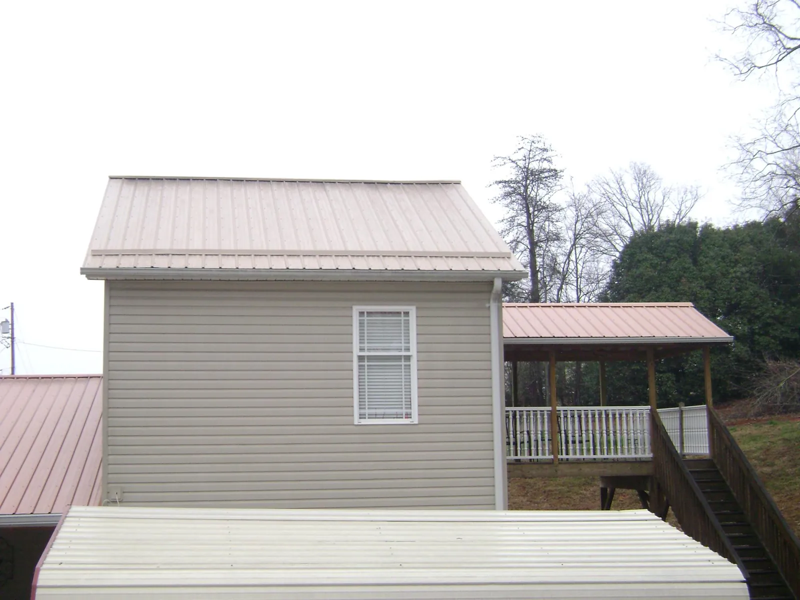 Tan metal roofs on a two story addition and attached porch, from a Roof Replacement job in Hanahan