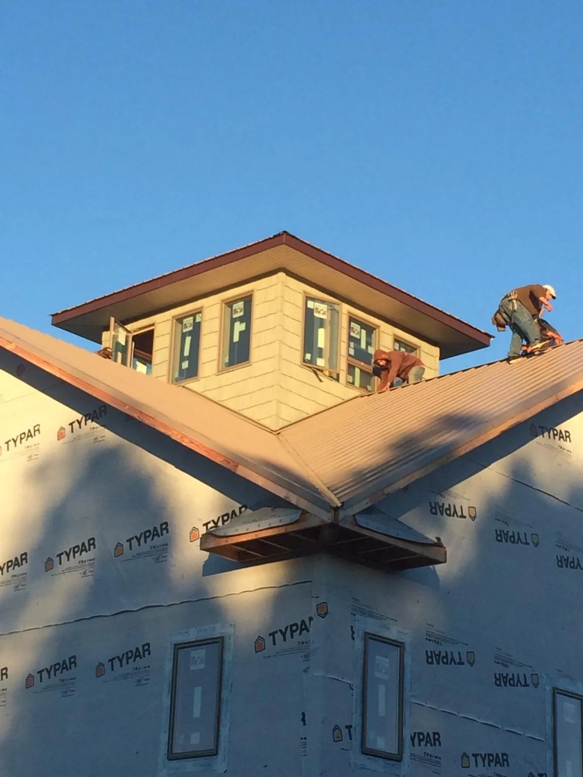 Roofers working around a rooftop cupola on a new metal roof at sunset — Roof Waterproofing in Hanahan by Roofing Brothers